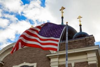 EUA encerram 2026 sem acolher refugiados perseguidos por religião, revela relatório 4 Bandeira dos EUA e duas cruzes no topo de uma igreja Foto Canva Pro