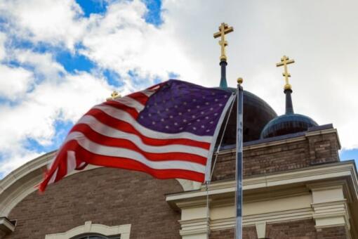 EUA encerram 2026 sem acolher refugiados perseguidos por religião, revela relatório 2 Bandeira dos EUA e duas cruzes no topo de uma igreja Foto Canva Pro