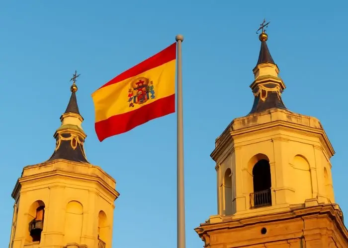 Aliança Evangélica Espanhola lança rede de apoio habitacional para famílias em situação de vulnerabilidade 1 Bandeira da Espanha entre as torres de uma igreja Foto Folha Gospel Canva IA